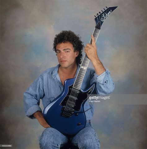 A Man Sitting On A Stool Holding An Electric Guitar And Posing For The