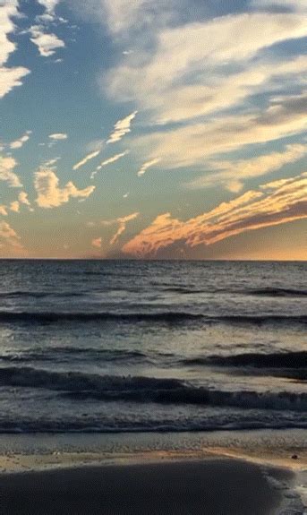 The Sun Is Setting Over The Ocean With Clouds In The Sky And Waves On