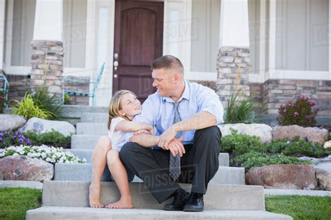 Caucasian Father And Daughter Sitting On Front Stoop Stock Photo