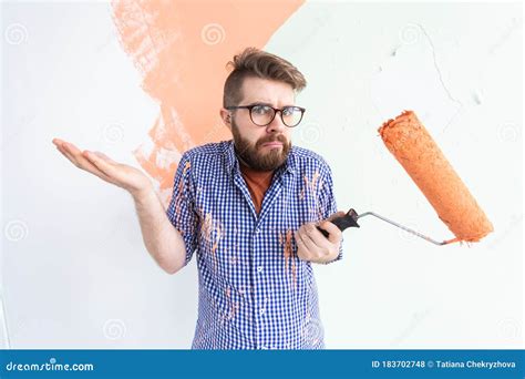 Confused Male Painting The Wall With Paint Roller Portrait Of A Funny