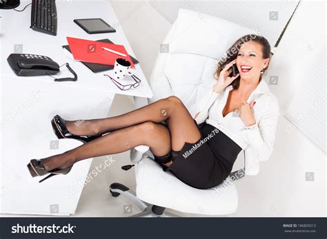 Sexy Business Woman Sitting On Office Chair And Talking On Mobile Phone