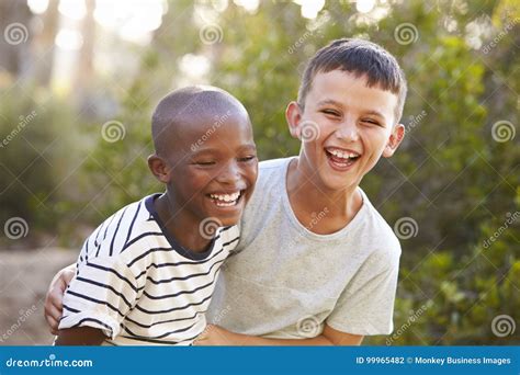 Portrait Of Two Boys Embracing And Laughing Hard Outdoors Stock Photo