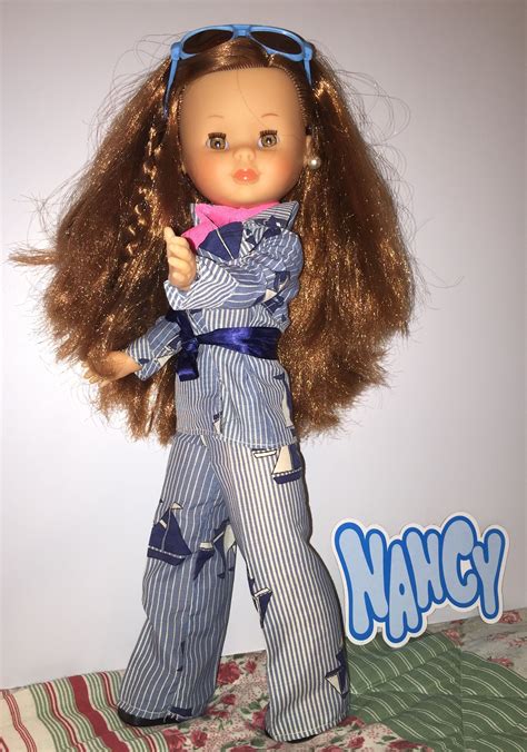 A Doll With Long Brown Hair Wearing Blue And White Striped Pants
