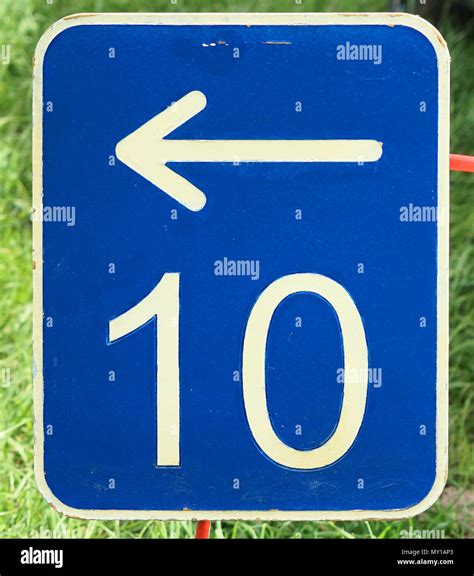 The Number Ten On A Blue Metal Plate With A White Arrow Pointing To The