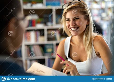 Happy Young University Students Studying With Books In Library Stock