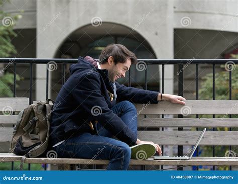 Young Man Sitting On Bench Smiling At Laptop Stock Image Image Of