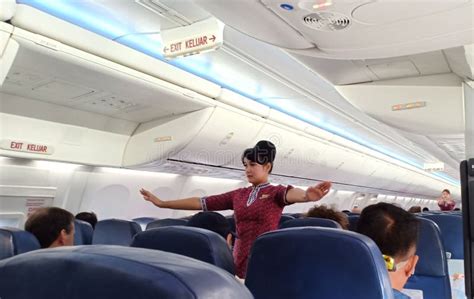 a female flight attendants on the aisle show passengers about safety instruction on board with