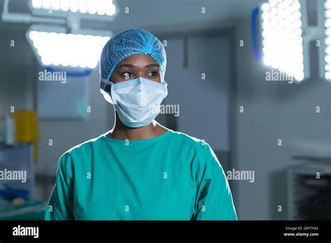 African American Female Surgeon Wearing Surgical Gown And Face Mask In