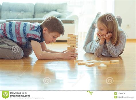 Two Happy Siblings Playing A Game With Wooden Blocks At Home Stock