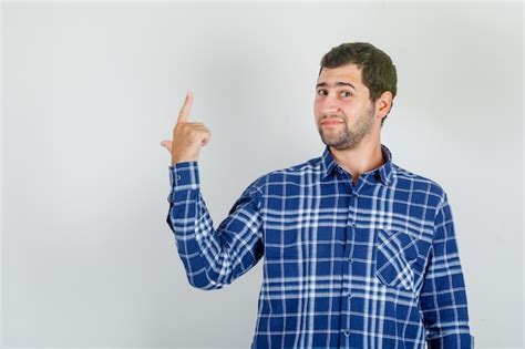 Free Photo Young Man Pointing To The Back And Smiling In Checked Shirt