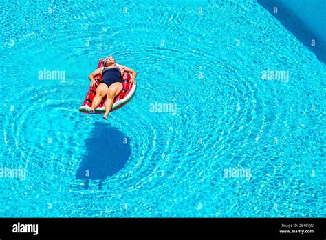 Senior Aged Lady Sleep And Relax Enjoying The Blue Water Of Swimming Pool Lay Down On Red