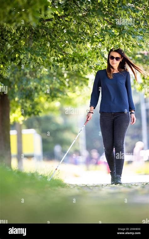 Blind Woman Walking On City Streets Using Her White Cane To Navigate The Urban Space Better And