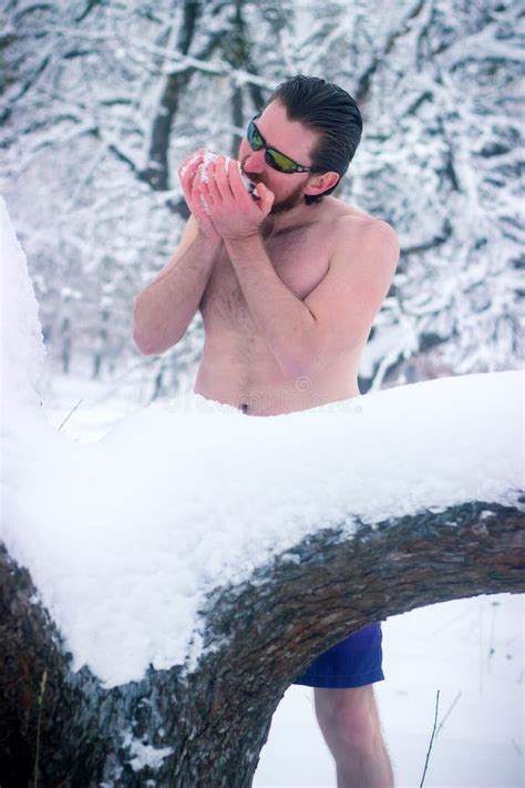 Naked Man With Sunglasses In The Winter Forest Eating Snow Stock Photo