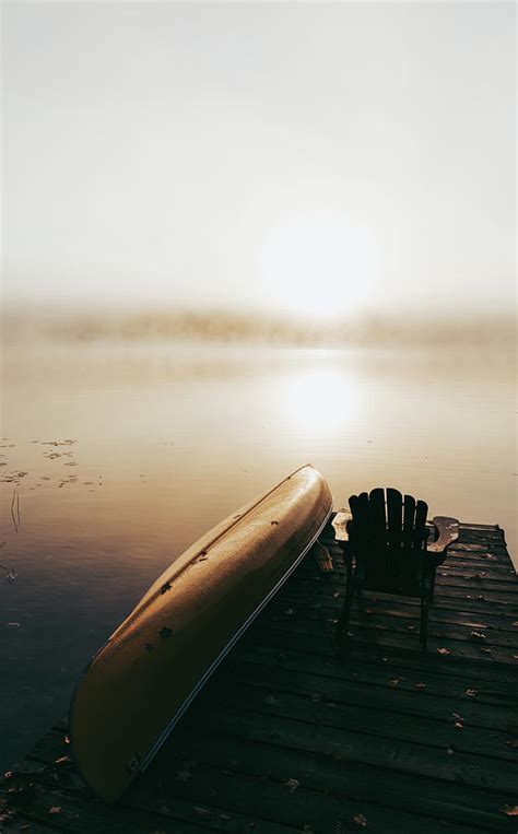 Empty Dock With Overturned Canoe On A Foggy Morning On A Calm Lake