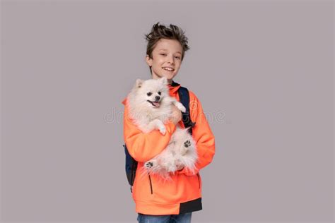 Caucasian Happy Teen Boy Hugging Spitz Dog Guy Is Standing In Sports