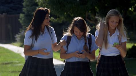 Three Teenage Girls Talking Walking And Text Messaging In School