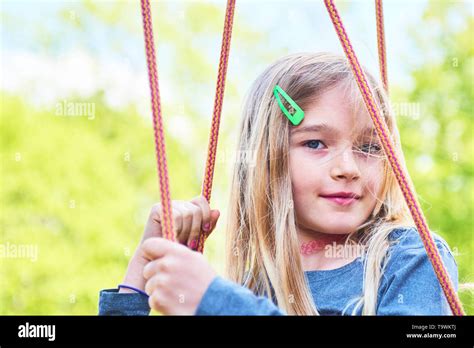 Portrait Of Little Cute Blond Girl With Blue Eyes Swinging Close Up