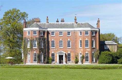 A Large Red Brick Building Sitting In The Middle Of A Lush Green Field