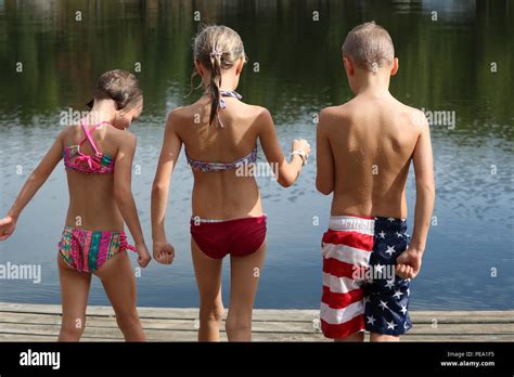 drei kinder in ihrer nassen badeanzug von hinten auf einem dock gesehen durch das wasser