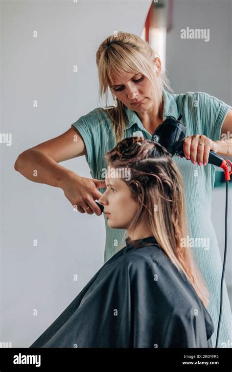 Hairdresser Blow Drying Clients Hair In Salon Stock Photo Alamy
