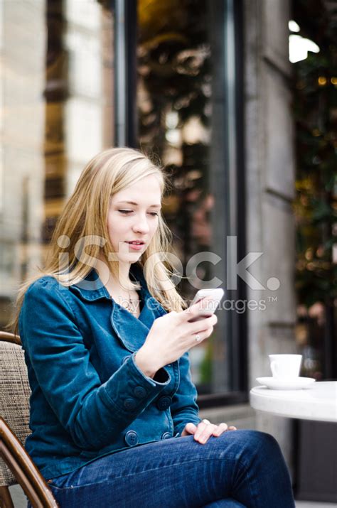 Young Woman Using Her Mobile Phone At A Sidewalk Cafe Stock Photo