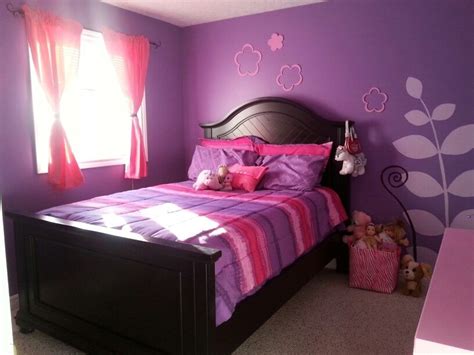 Purple and pink kids bedroom in attic features a barbara barry simple scallop pendant hanging over a colorful floral headboard on full bed dressed in white and purple hotel duvet and shams, purple pillow cases and a red flower pillow placed in front of window flanked by small white bedside tables topped with robert abbey delta amethyst glazed table lamps. Pink and purple girls room | Purple girls bedroom, Purple ...