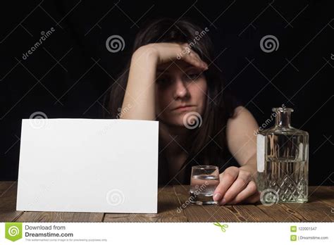 sad girl sitting with a glass in her hand bottle and alcohol black background clean sheet