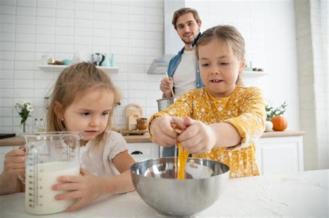 Padre E Hijas Sonrientes Que Cuecen En La Cocina Y Divertirse Imagen De