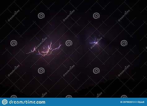 Lightning Discharges In Stormy Sky Under Dark Rain Clouds At Night