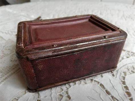 An Old Brown Leather Box Sitting On Top Of A White Table Cloth Covered