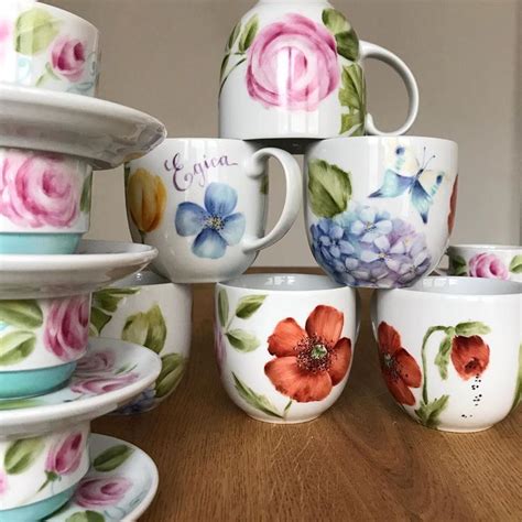 A Table Topped With Cups And Saucers Covered In Flowered Designs On Them
