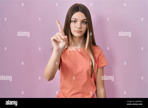 Teenager Girl Standing Over Pink Background Pointing With Finger Up And Angry Expression
