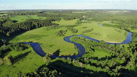 Top View Of A Winding Small River Flowing Through Green Meadows Stock