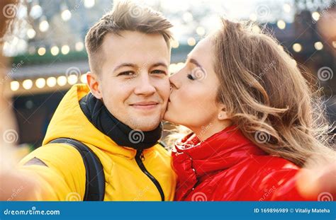 Young Romantic Couple In Love Making Selfie Smile To To The Camera Woman Kissing In Cheek Her