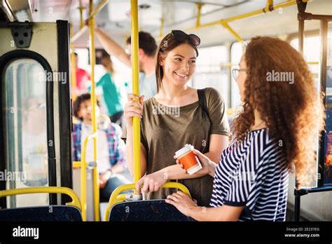 Two Beautiful Best Friends Are Talking While Standing In A Bus Full Of