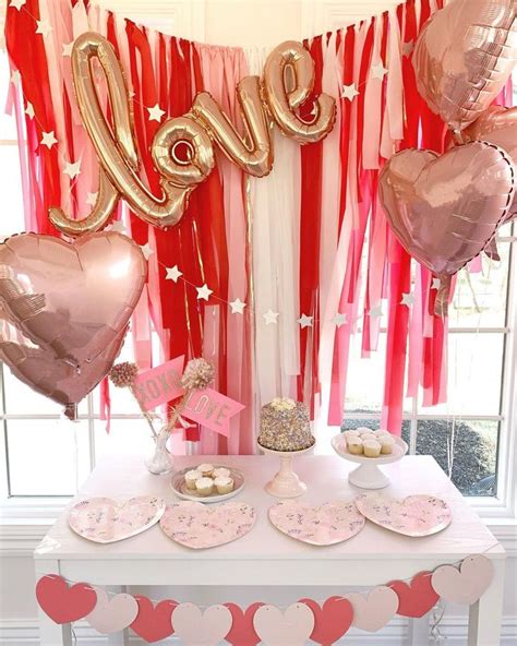 A Table Topped With Lots Of Pink And Gold Heart Shaped Balloons Next To