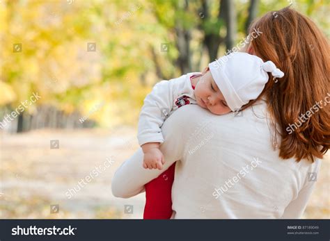 Sleeping Little Girl On Mothers Shoulder In Autumn Park Stock Photo