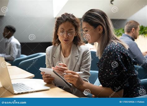 Focused Millennial Women Discuss Business Plan In Office Stock Photo