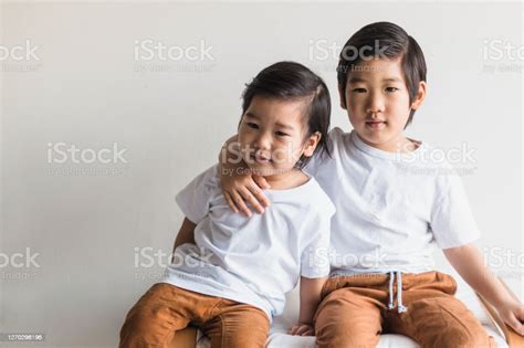 Sitting On Bench Older Brother Puts Arm Around Younger Brother Stock