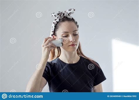 Cute Girl With A Headband Massages Her Face With A Microcurrent Device