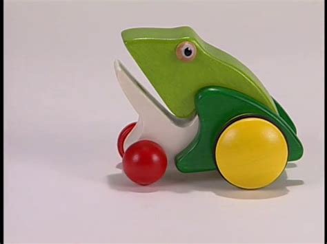 A Green Frog Toy With A Red Ball On The Ground Next To Its Head