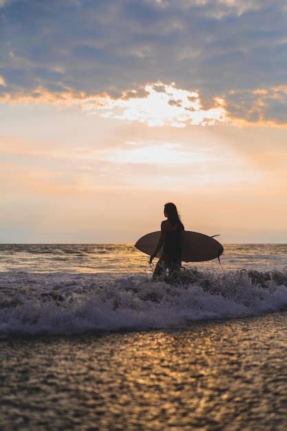 Free Photo Woman Surfer With Surfboard On The Ocean At Sunset