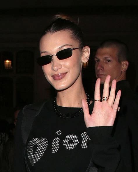 A Woman In Black Shirt And Sunglasses Holding Her Hand Up To The Side