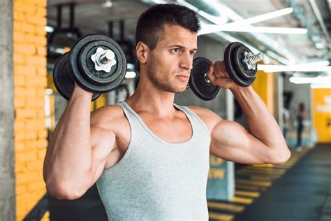 Young Man Doing Exercise With Dumbbells For Strengthening His Shoulder