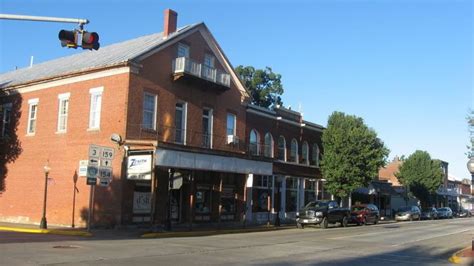 An Old Red Brick Building On The Corner Of A Street With Cars Parked In