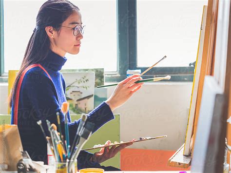 Side View Of A Female Artist Painting In An Art Studio Of College