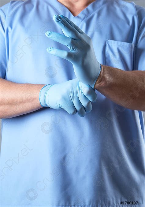 Doctor In A Blue Uniform Puts On Sterile Latex Gloves Stock Photo