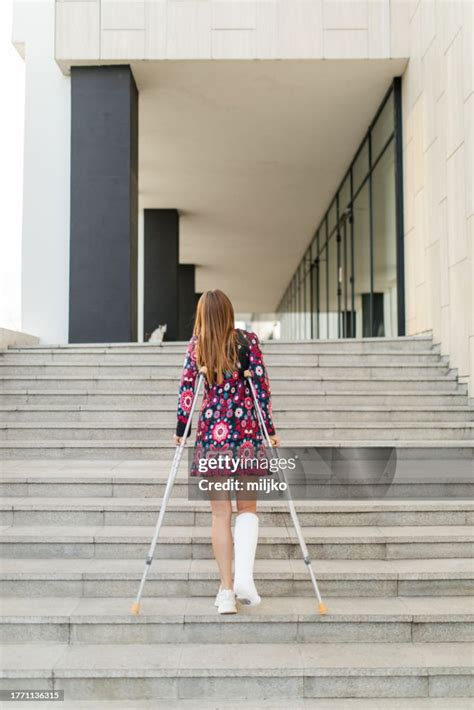Woman With One Leg In Cast And Crutches Walking Up The Stairs High Res