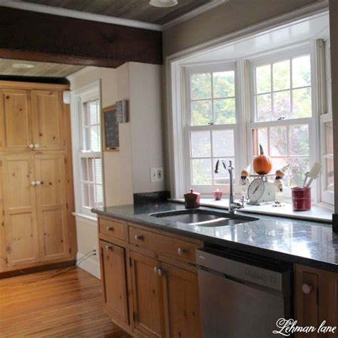 A Kitchen With Wooden Cabinets And Black Counter Tops Next To A Window