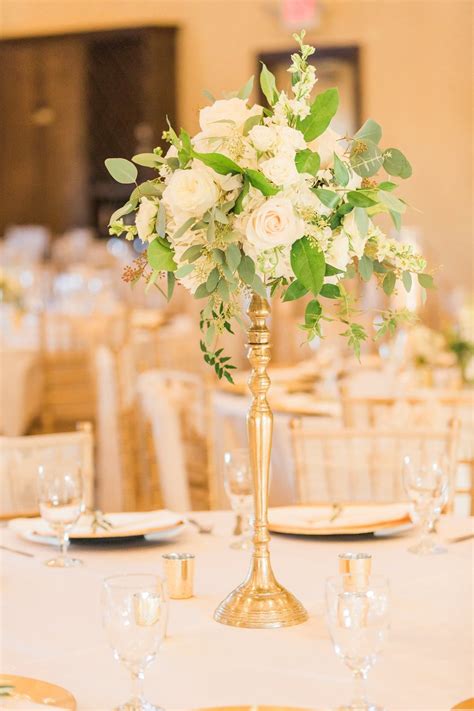 A Gold Candelabra With Greenery And White Roses Make A Beautiful